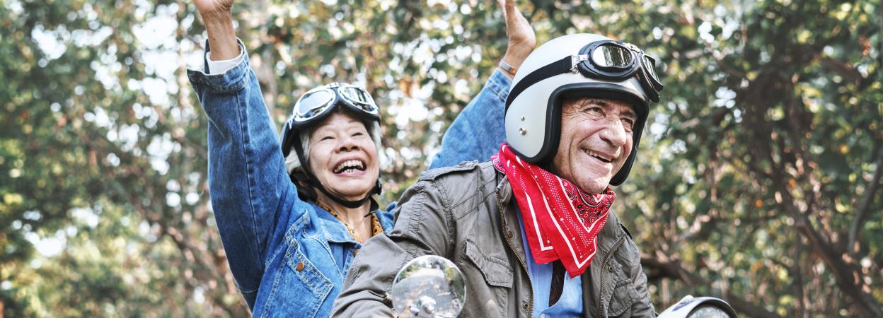 Headerbild mit fröhlichem Seniorenpaar auf einem Motorrad