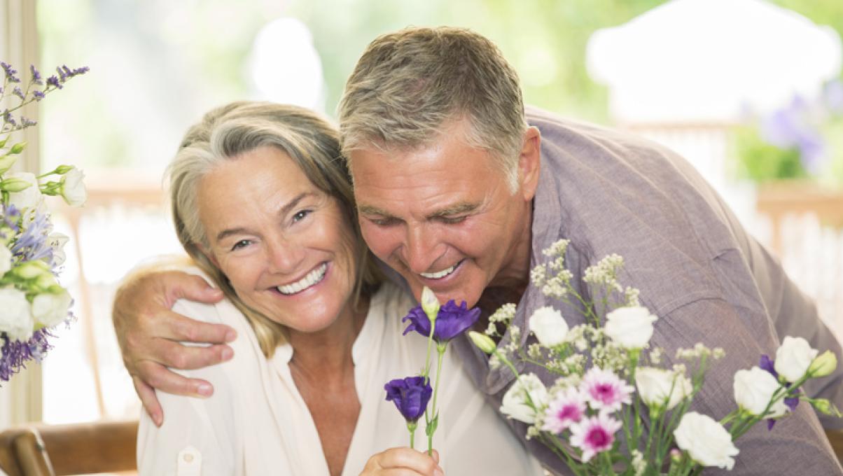 Ein älteres Paar riecht an einem Blumenstrauß